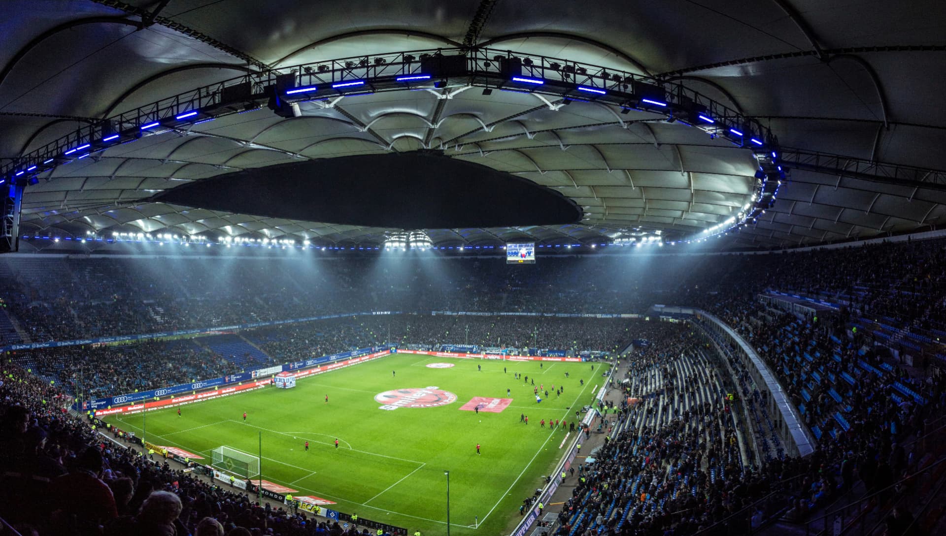 Fullsatt fotballstadion i Hamburg under en kveldskamp sett fra tribunen