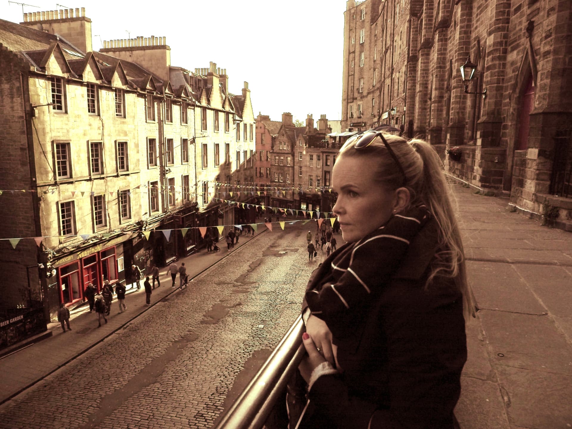Ann ser utover en brolagt gate med vimpler i Edinburgh i Skottland