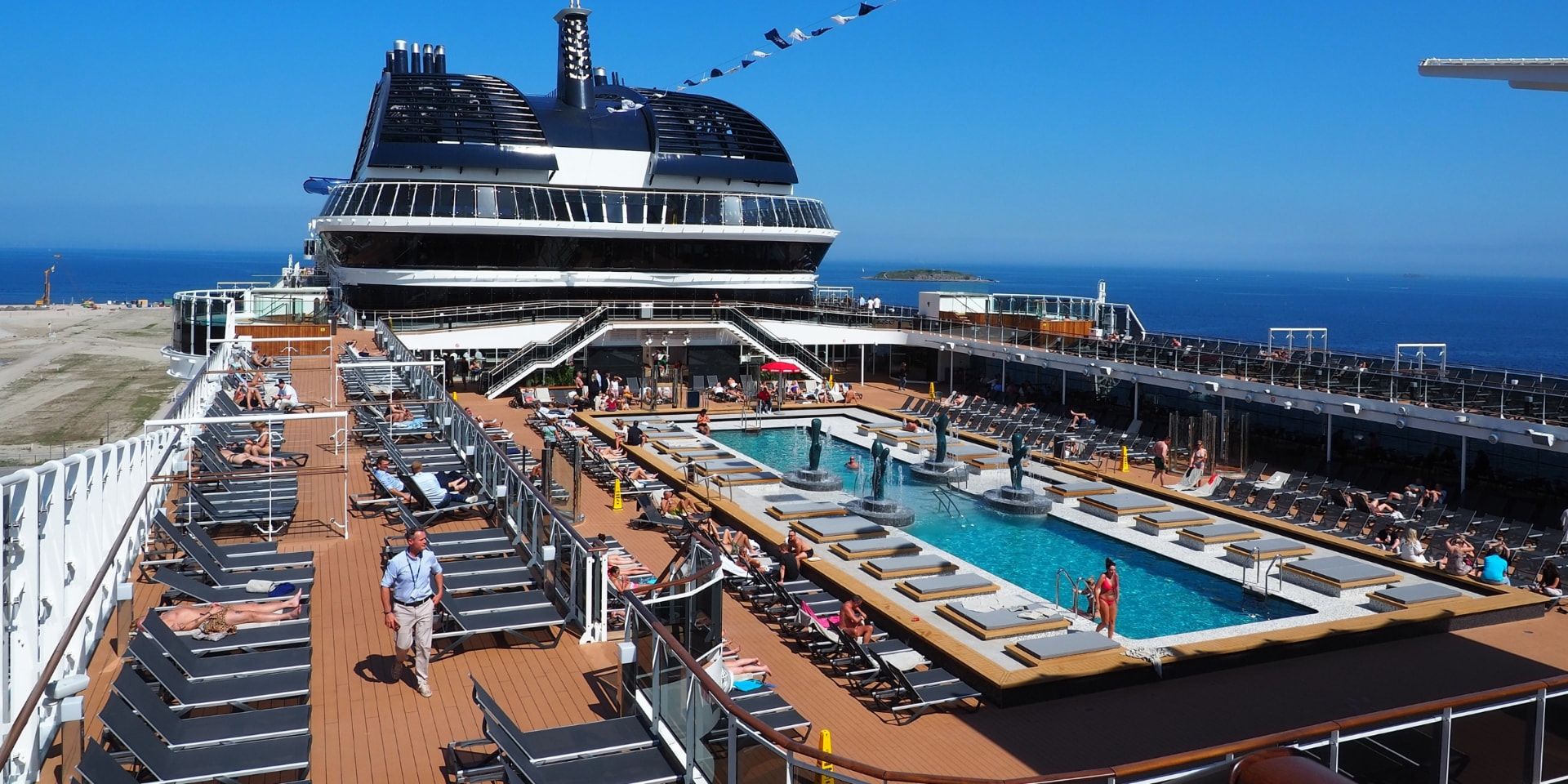 Soldekk med basseng om bord på et cruiseskip på vei ut fra havn