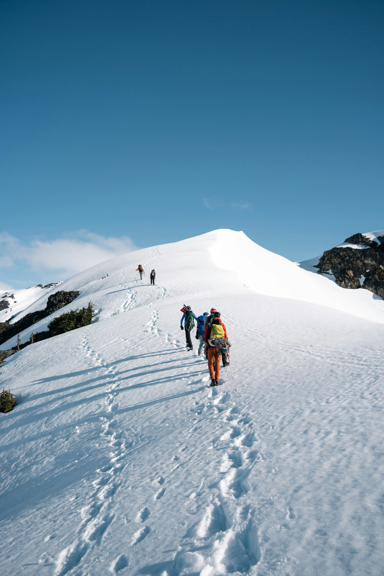 Gruppe på vei opp en snødekt fjellrygg i klart vintervær
