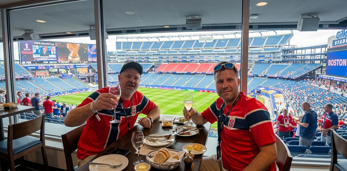 To kolleger i norske fotballdrakter med utsikt over stadion fra VIP-losje