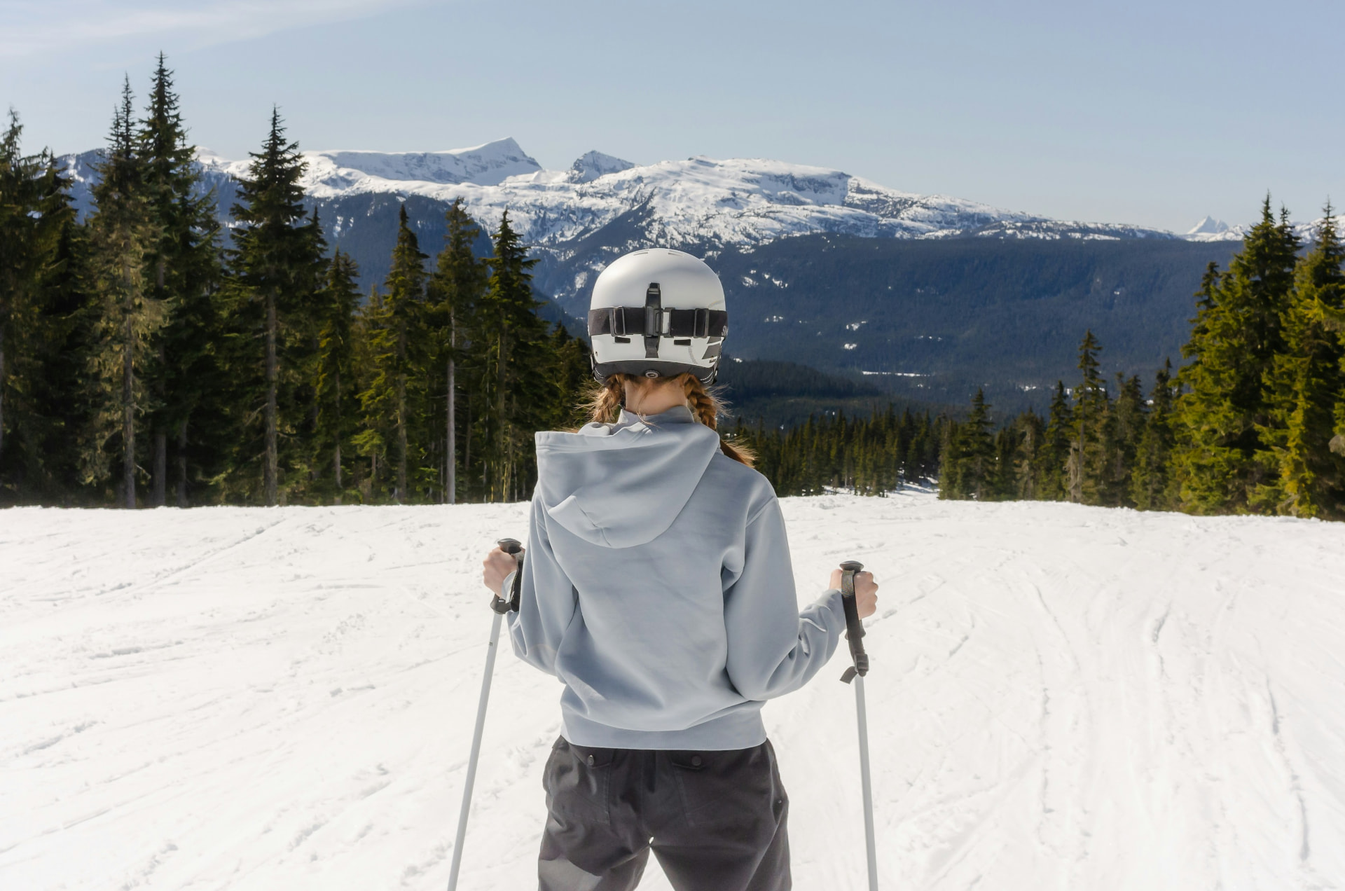 Skikjører i bakken med snødekte fjell i bakgrunnen