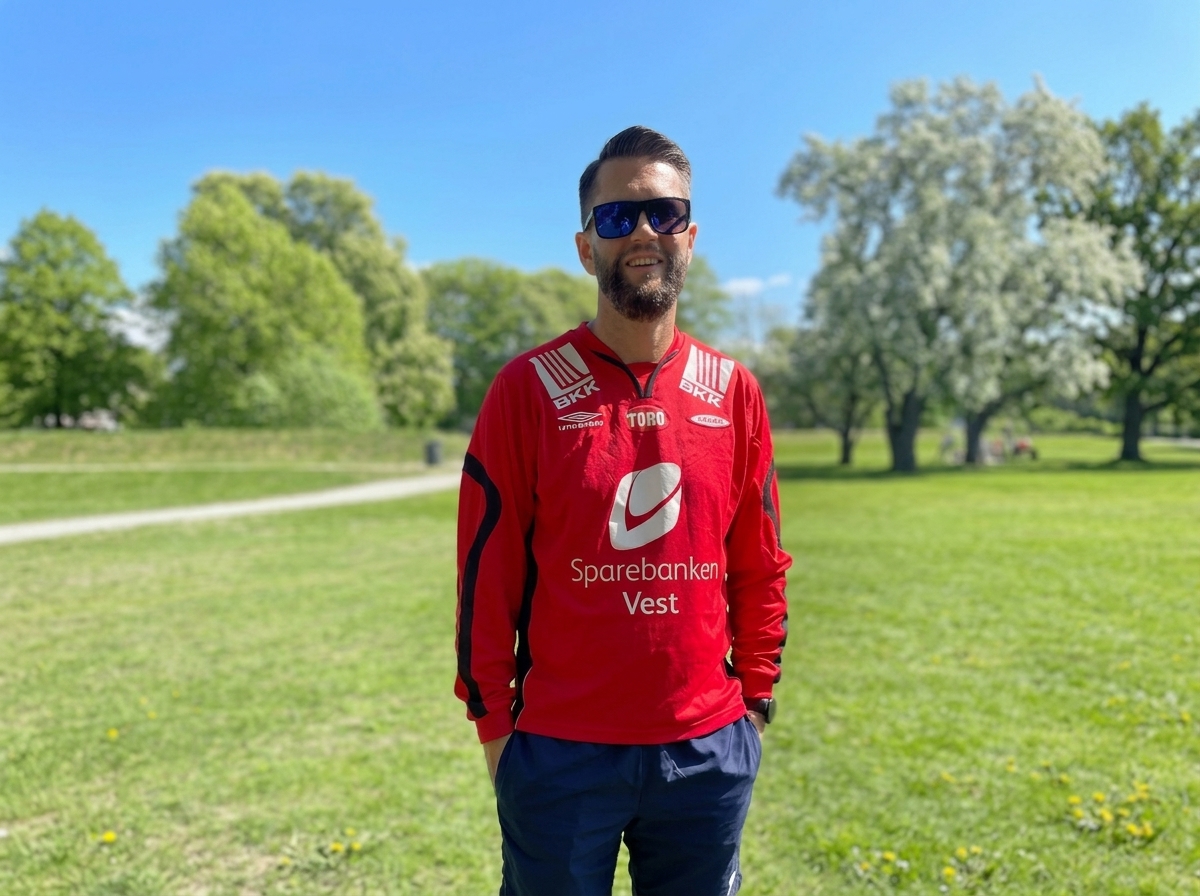 Kollega i rød fotballdrakt i en grønn park i Bergen på en solrik dag
